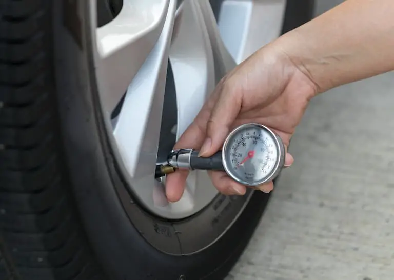 measuring car tire pressure with air gauge