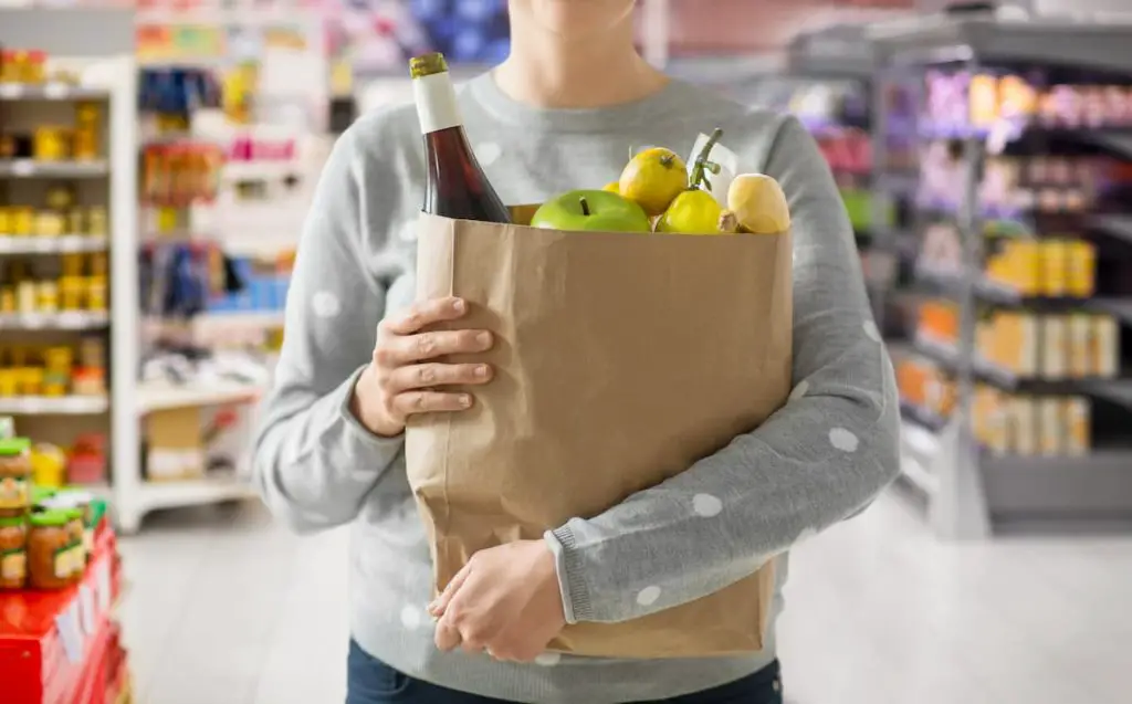 woman with paper bag full of food over supermarket