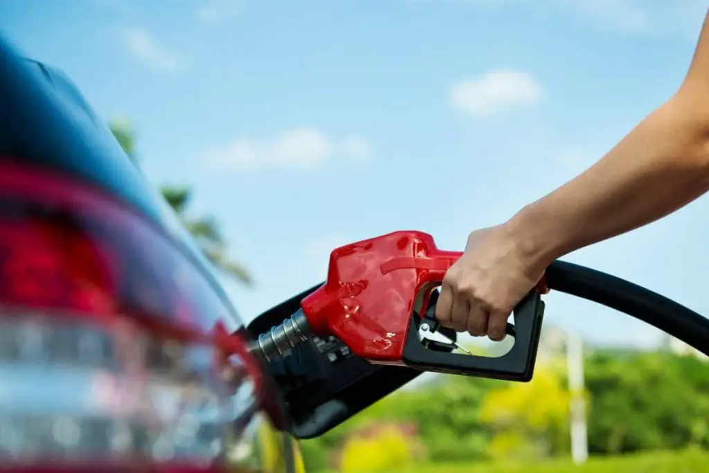 hand refilling the car with fuel