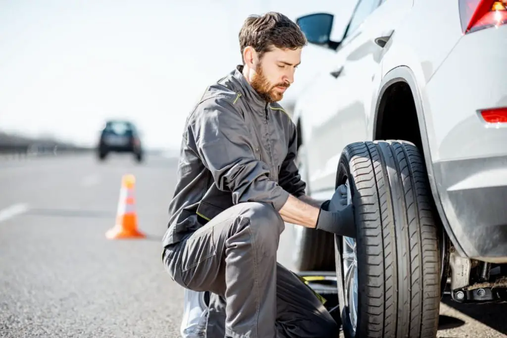 road assistance worker changing car wheel on the highway