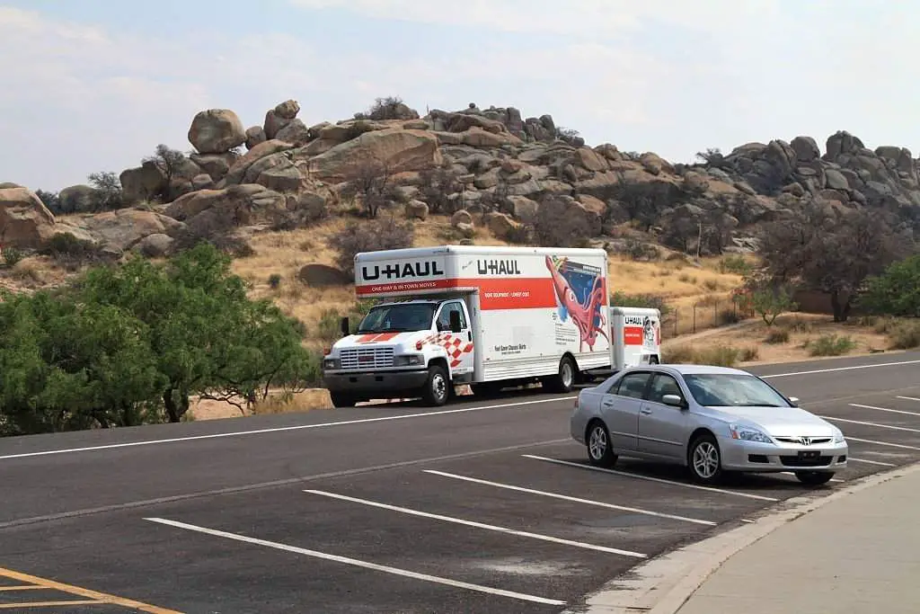A U-Haul truck with pull along trailer is parked in a roadside