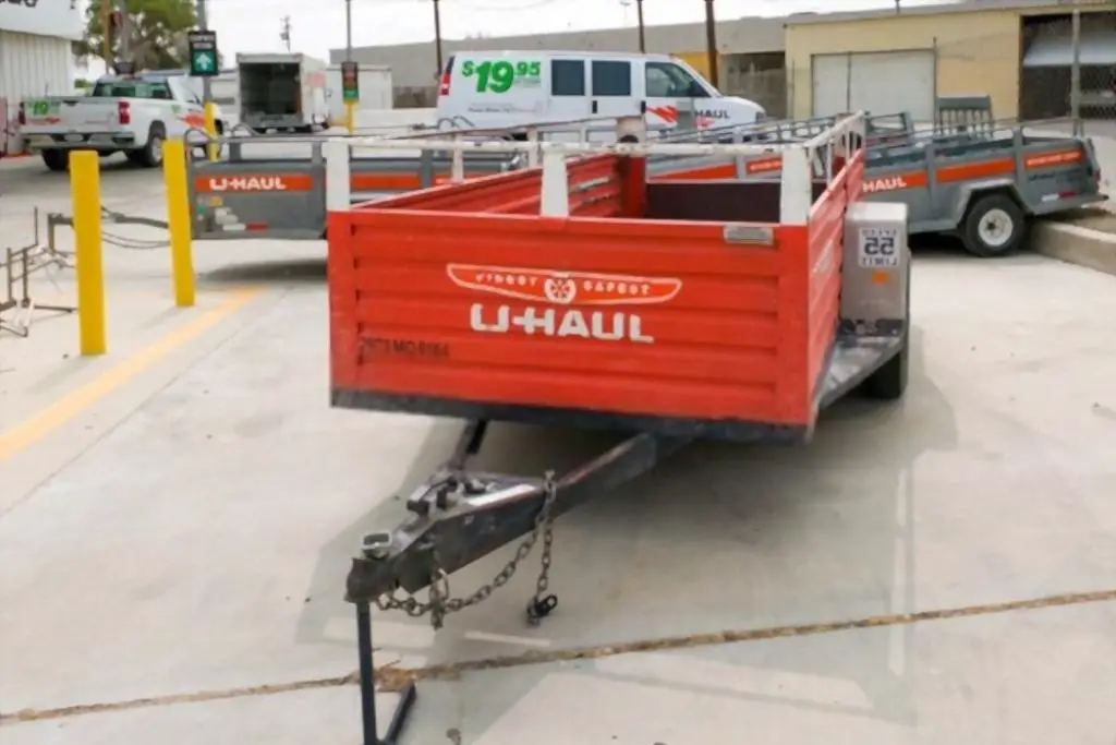 a small orange open trailer on the lot of U-haul rentals