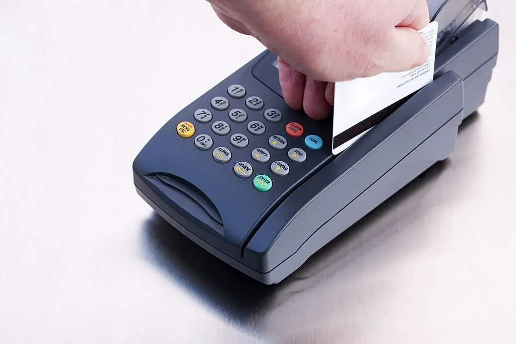 hand running a credit card through a credit card processing machine