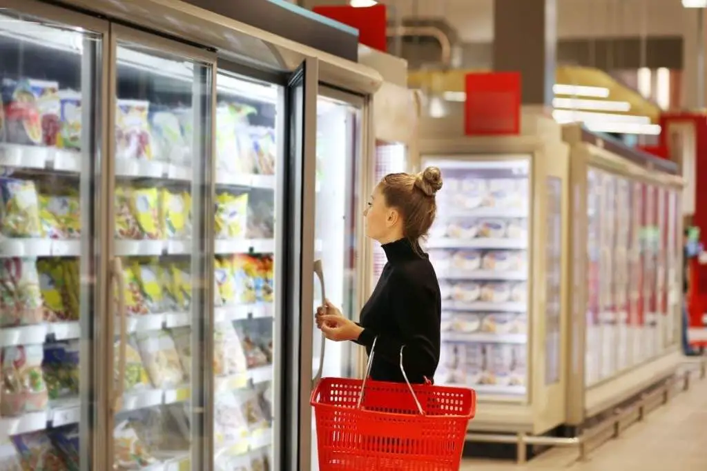 woman choosing frozen food from a supermarket freezer