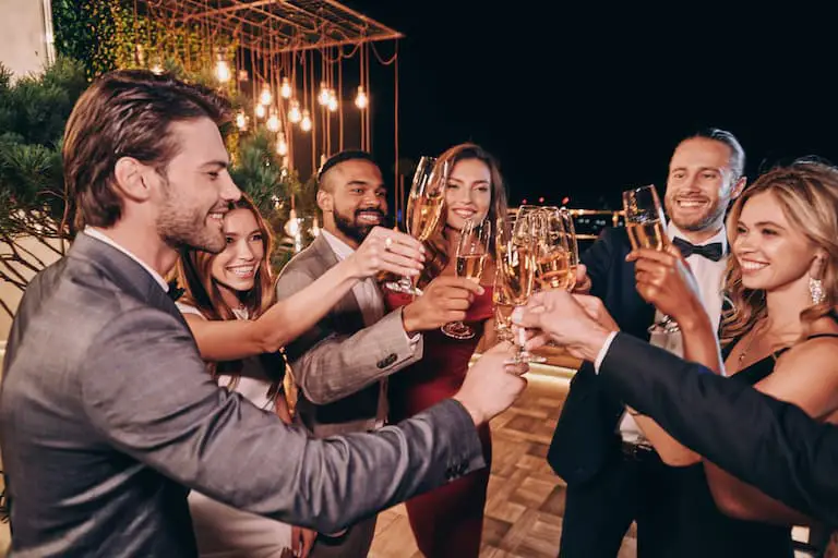 group of beautiful people in formalwear toasting with champagne and smiling